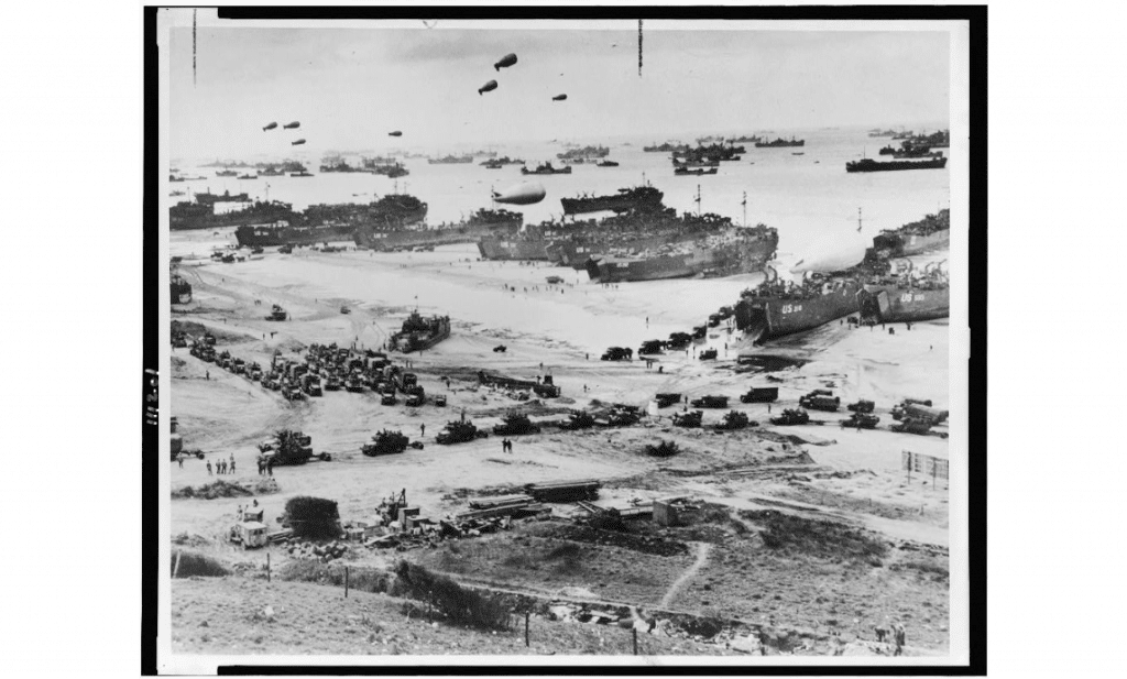 Bird's-eye view of landing craft, barrage balloons, and allied troops landing in Normandy, France on D-Day