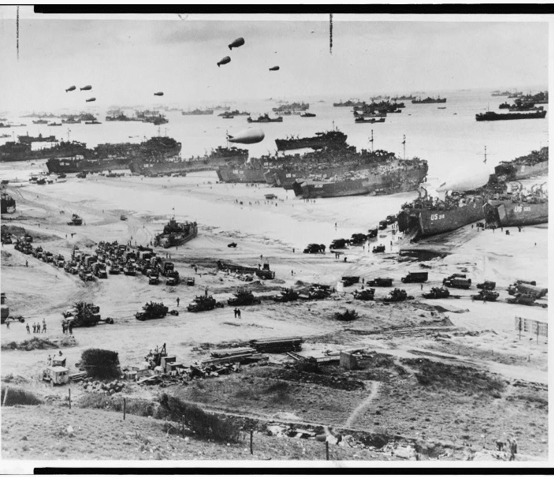 Bird's-eye view of landing craft, barrage balloons, and allied troops landing in Normandy, France on D-Day
